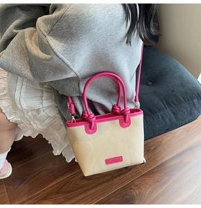 Detail der Canvas-Eimertasche mit pinkfarbenem Lederbesatz und Logo-Tag am Schultergurt