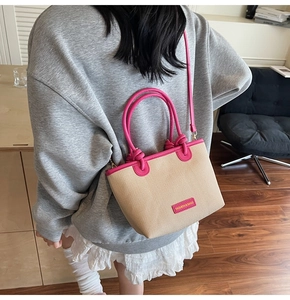 Detail der beigen Strohtasche mit leuchtend rosa Lederriemen und Handgriff