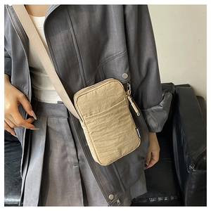 Detail of khaki nylon phone bag with adjustable shoulder strap and fashion label