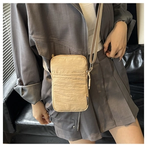 Detailed view of beige mini crossbody phone bag in textured fabric with adjustable strap