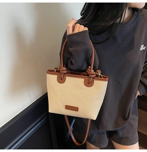 Nahaufnahme der beigen Strohtasche mit braunen Ledergriffen und Markenetikett