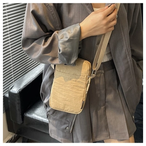 Khaki nylon mini crossbody bag shown on model in a modern professional office setting