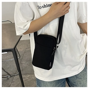 Detail view of black nylon crossbody phone bag with adjustable strap and fashion label