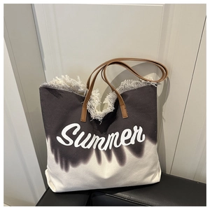 Macro detail of canvas tote bag featuring raw fringe edges and white Summer print text