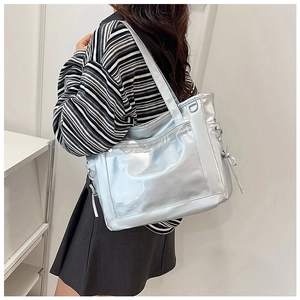 Silver metallic tote bag detail with transparent front pocket and side drawstring bows