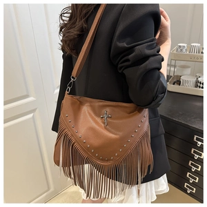 Vue détaillée du sac à bandoulière marron avec franges, rivets et breloque croix rétro