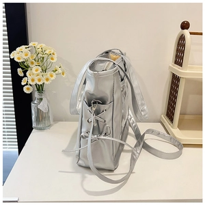 Detail of silver metallic tote bag featuring stylish side criss-cross lacing and sleek finish
