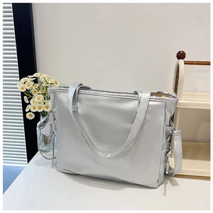 Detail of silver metallic tote bag with detachable strap and top handles in home setting
