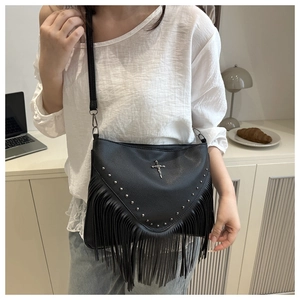 Détail de la besace noire en cuir grainé avec rivets métalliques et longues franges