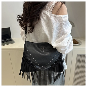 Détail du sac noir à franges avec clous argentés et un pendentif croix en métal