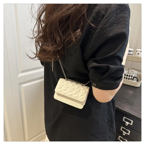 Detail of off-white quilted crossbody bag with gold chain strap on black shirt