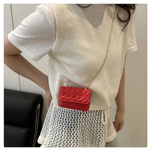 Detail of red quilted mini bag with gold chain strap on white knitted sweater outfit