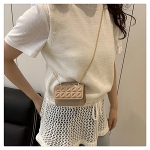 Close-up of beige quilted crossbody mini bag with gold chain strap on person
