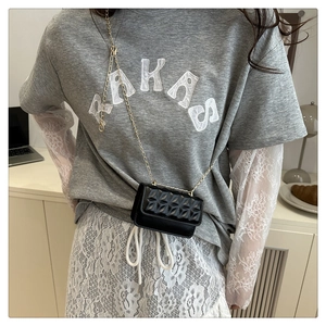 Detail of mini black quilted crossbody bag with gold chain strap on model's shoulder