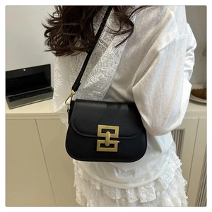 Detail of a black leather crossbody bag featuring a golden geometric lock and matte finish