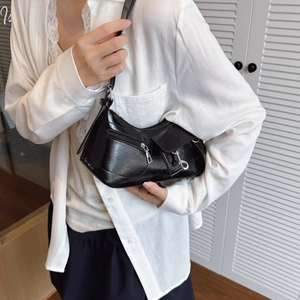 Sac baguette noir brillant à la mode avec détails argentés porté par un modèle