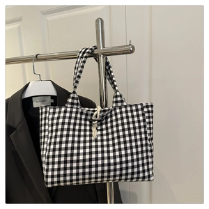Close-up of black and white checkered canvas tote with toggle closure and woven loop