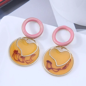 Detail of geometric round drop earrings with yellow translucent resin and gold heart frame