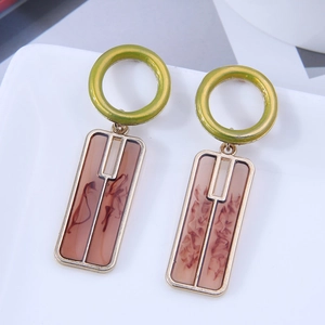 Detail view of geometric drop earrings featuring green rings and resin rectangle charms