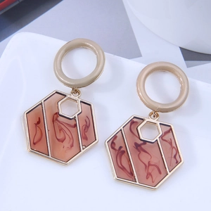 Detailed view of geometric hexagonal drop earrings with marble resin inlays on a tray