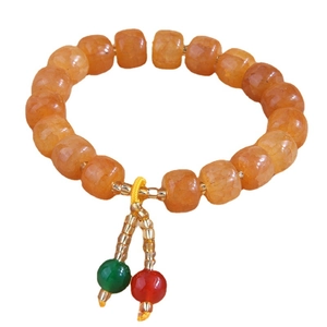 Bracelet en résine orange avec perles dorées et pompons colorés sur un fond blanc pur