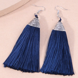 Close-up of navy blue fringe tassel earrings with silver engraved metal caps