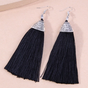 Close-up of black fringe tassel earrings with vintage silver metal caps and bead details