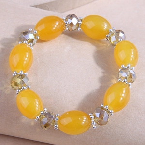 Detail of yellow oval beads and faceted crystal beads with silver flower spacers on bracelet