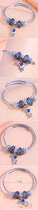 Detail view of silver steel bracelet with astronaut charm and purple starry beads