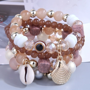 Detailed macro view of bohemian multilayer bracelets with shell, conch, and evil eye charms