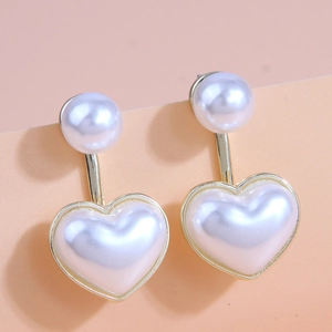 Élégantes boucles d'oreilles dorées avec perle ronde et pendentif cœur sur fond pastel