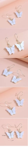 Détail de boucles d'oreilles papillon en acrylique avec crochets dorés et marbrures