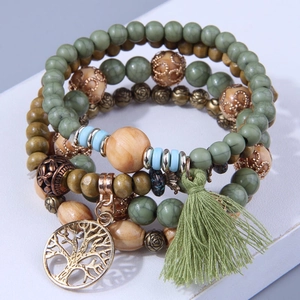 Detail of bohemian layered beaded bracelet with green tassels and a tree of life charm