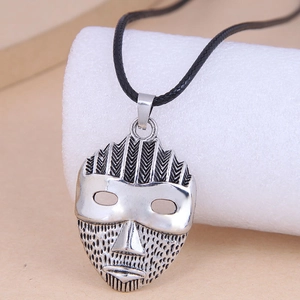 Detail of vintage tribal mask pendant in antique silver finish on black cord necklace