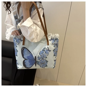 Detail showing the light blue canvas tote bag with butterfly prints and frayed edges