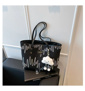 Detail of black tote bag with wave embroidery and cute white cloud plush pendant charm
