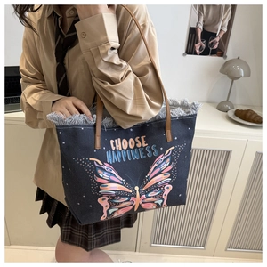 Detail of blue canvas tote bag featuring butterfly print and frayed fringe trim