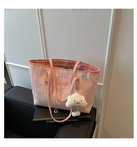 Close-up of pink embossed leather tote bag with rainbow stitching and plush charm