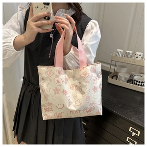 Detail of a beige canvas tote with pink cartoon bear prints and stylish webbed handles