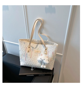 Detail of white tote bag with embossed floral patterns, wave embroidery, and cloud charm
