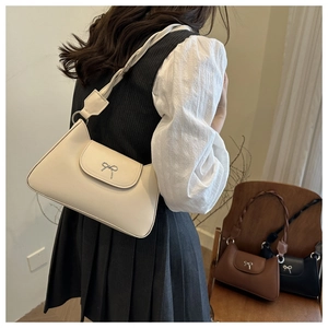 Detail of trendy crescent underarm bag featuring a woven strap and metal bow buckle