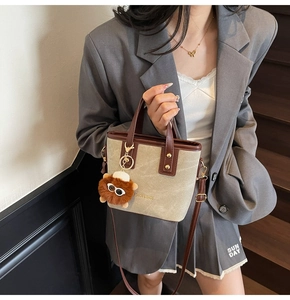 Detail of canvas and leather crossbody bucket bag featuring a cute lion bag charm