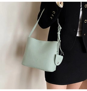 Close-up of mint green litchi grain leather bucket bag with brand charm and shoulder strap