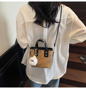 Detail of camel suede bucket bag with black leather straps and plush monster charm