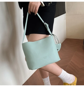 Detail of mint green lychee texture bucket bag with adjustable strap and heart charm