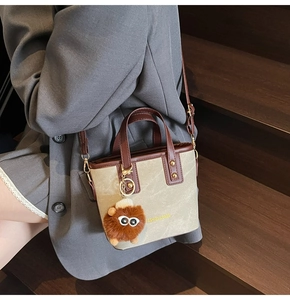 Detail of retro canvas tote bag with brown leather trim and cute monster charm