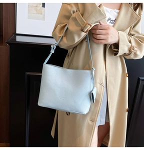Close-up of light blue pebble grain leather bucket bag with debossed logo and adjustable strap