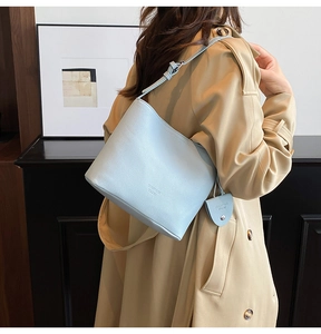 Close-up of light blue lychee pattern leather shoulder bag with mini round charm pendant