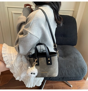 Chic canvas bucket bag with contrast leather handles and white pom-pom charm on model