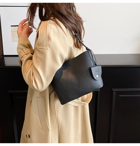 Close-up of black lychee grain leather bucket bag with gold hardware and small pouch